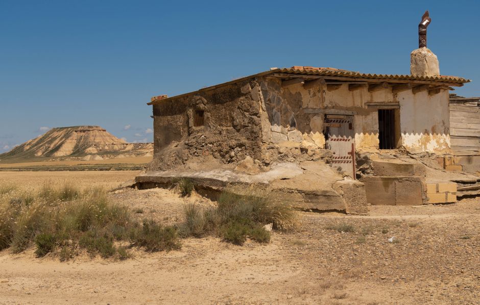 Casa de piedra abandonada en un paisaje desértico español desolado bajo un cielo azul brillante.