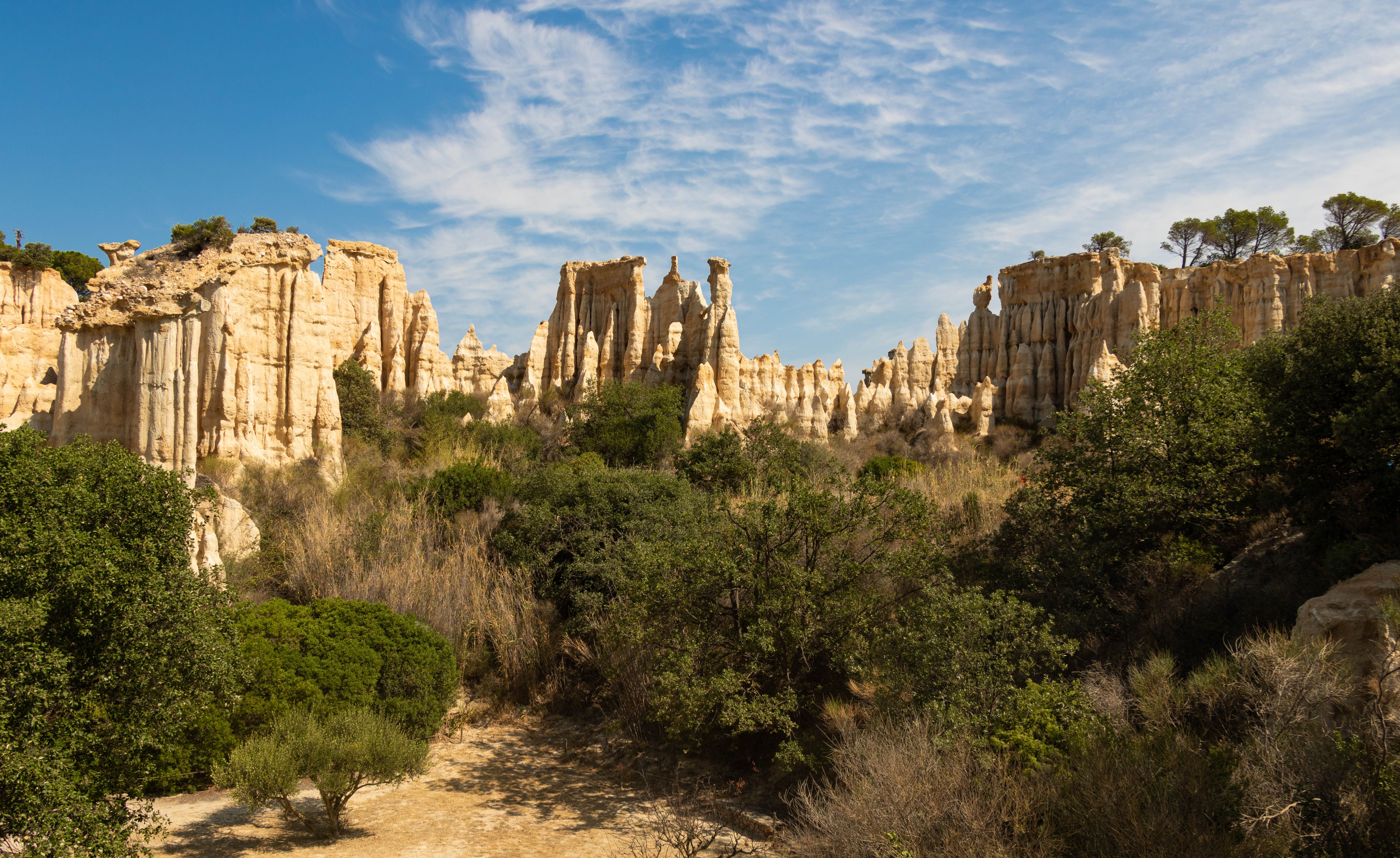 View of unique geological rock formations in Southern France, surrounded by greenery under a bright sky.