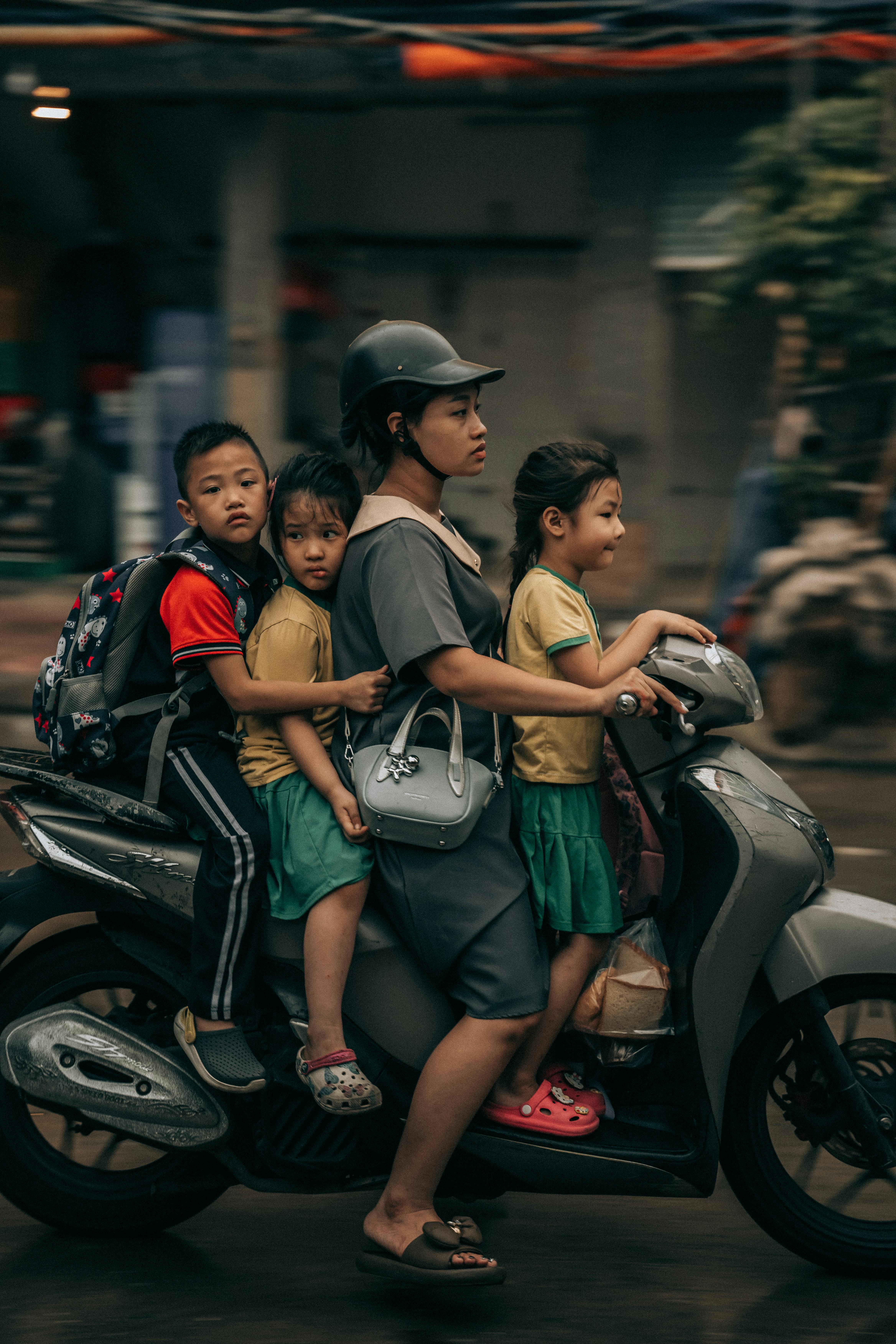 A family of four rides a scooter through Hanoi's busy streets, capturing the vibrant city life.