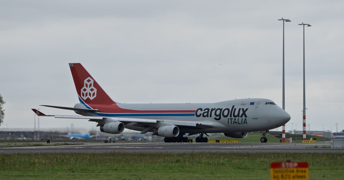 Cargolux Italia cargo plane taxiing on a runway at an airport with overcast skies.