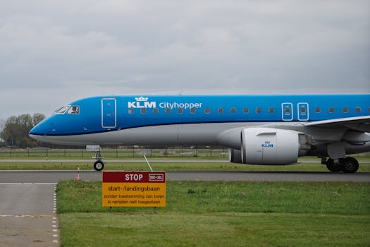Side view of KLM Cityhopper aircraft on a runway with a stop sign, overcast day.