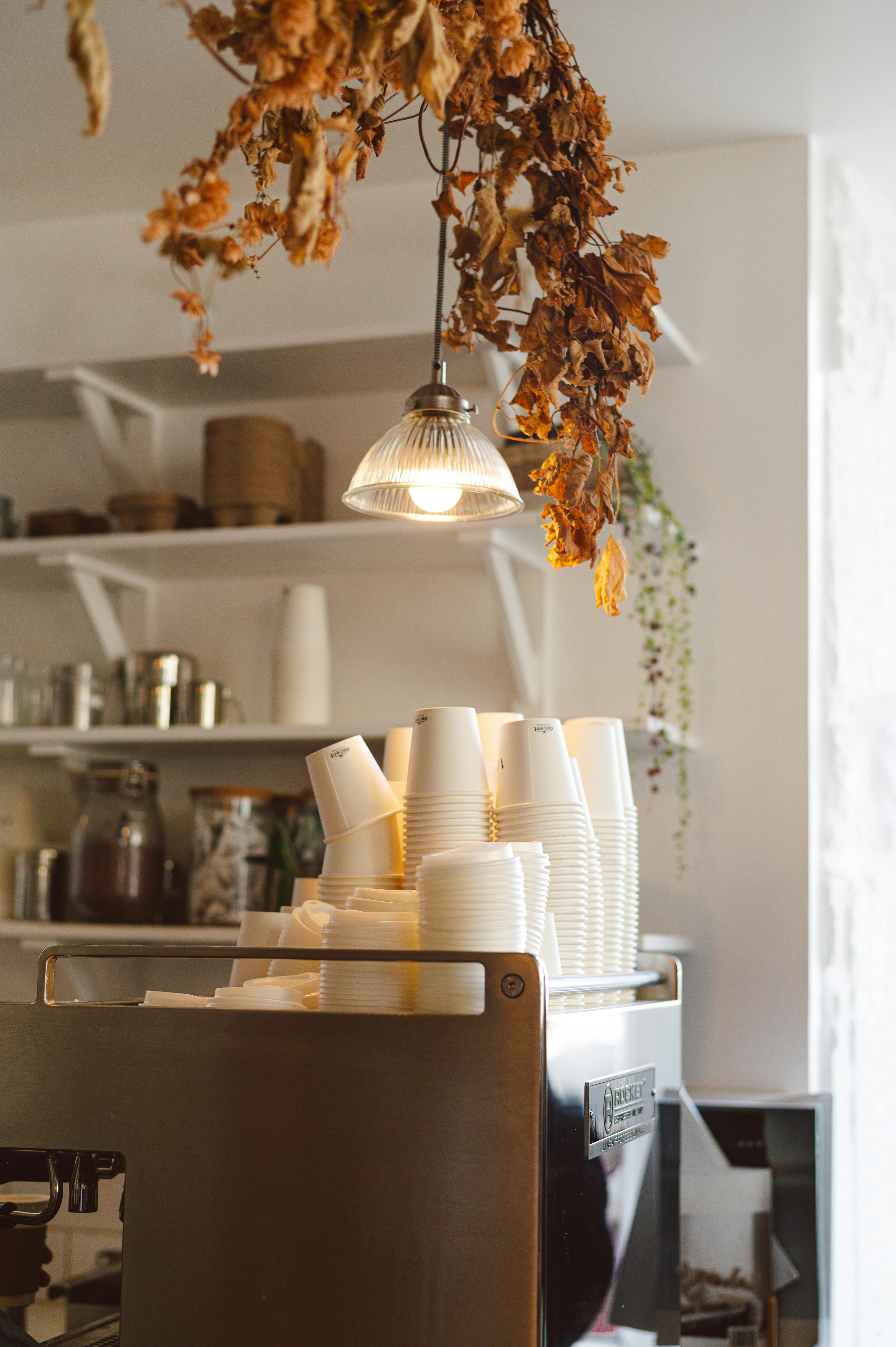 A warm coffee shop interior in Dunkeld, Scotland, showcasing autumn decor with stacked cups.