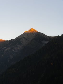 Tranquil alpine sunrise with a sunlit mountain peak in Holzgau, Austria.