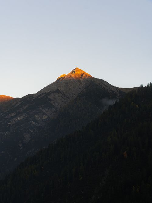 Free Tranquil alpine sunrise with a sunlit mountain peak in Holzgau, Austria. Stock Photo