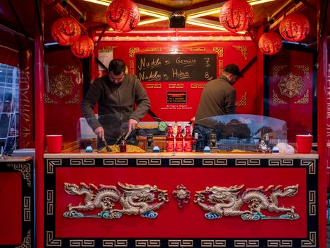 Vibrant Asian food stall offering noodles with decorative dragons and lanterns, creating an exotic street market vibe.