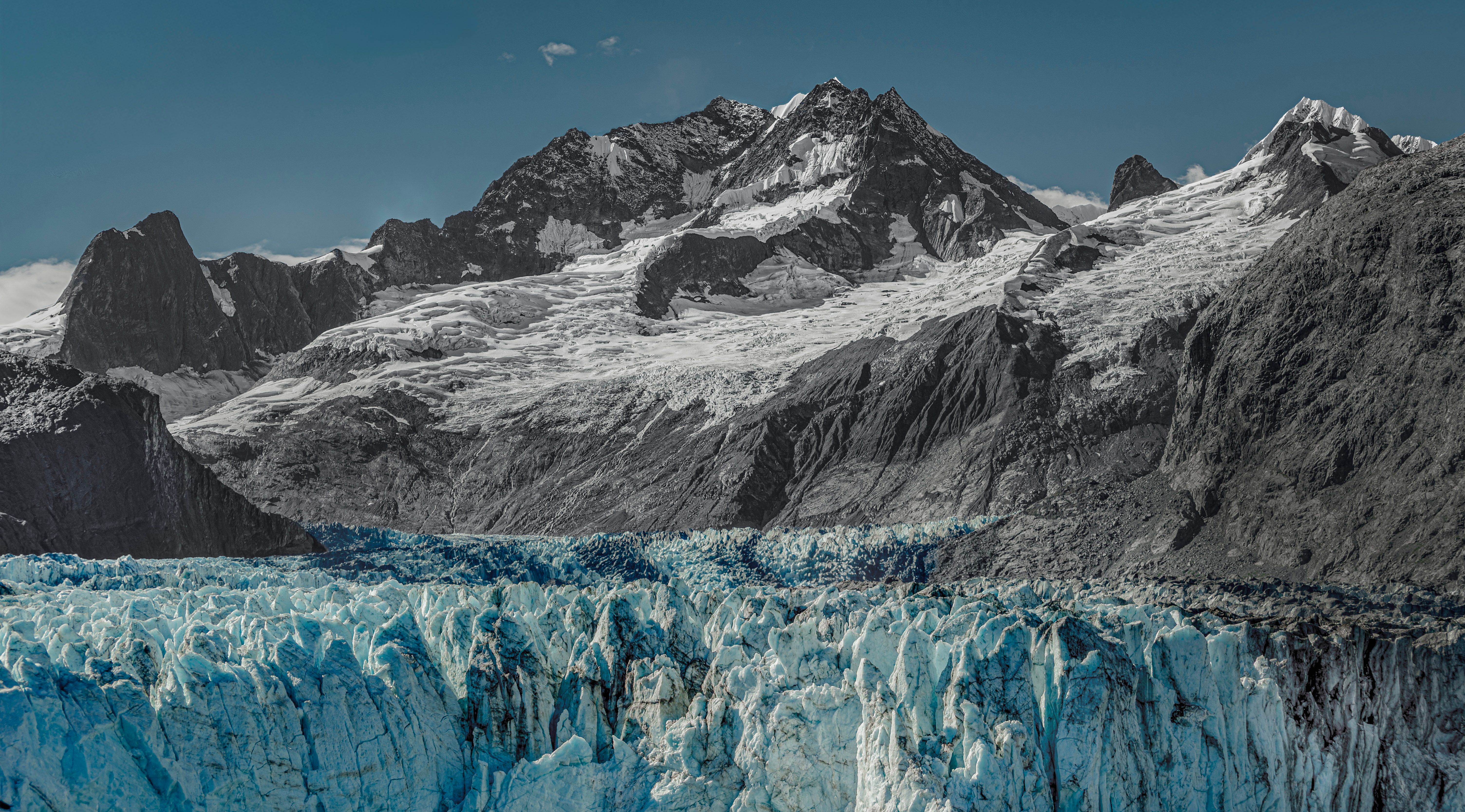 Majestic Alaskan glacier with rugged mountains showcasing natural beauty and global warming impact.
