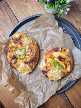 Freshly baked homemade pizzas with cheese, olives, and green pepper toppings on a rustic tray.