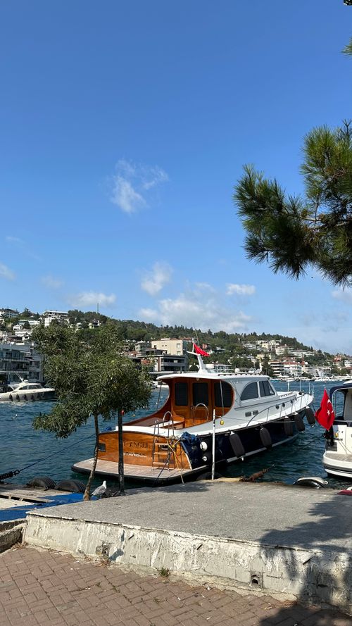 Free Serene view of boats docked by a hillside waterfront under clear blue skies. Stock Photo