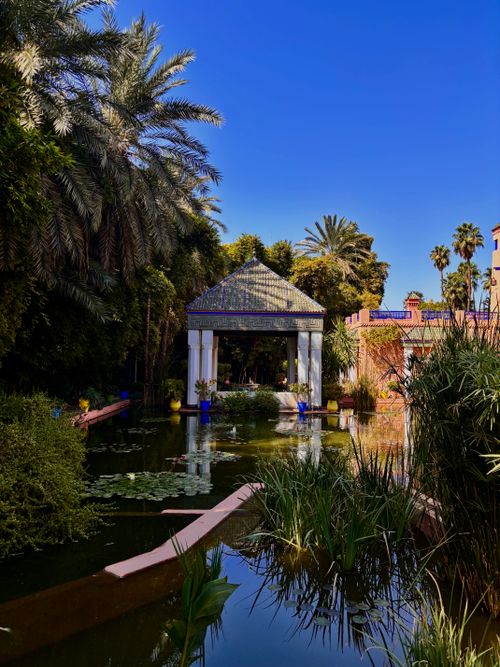 Free Beautiful pavilion surrounded by lush greenery and reflection pond in a tropical garden setting under clear skies. Stock Photo
