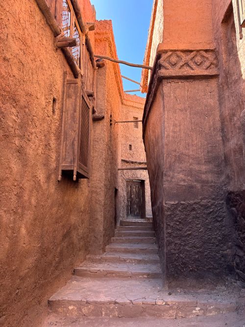 Free A narrow alley with traditional adobe architecture under a bright sky in Morocco. Stock Photo
