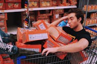 一名男子懒洋洋地躺在超市过道里装满丸子拉面的购物车中