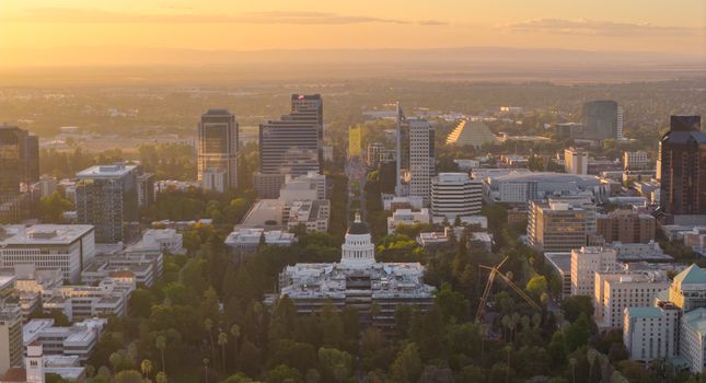 Aerial view of Sacramento cityscape with State Capitol and Tower Bridge at sunset.