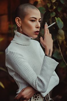 一位时尚女人穿着白色毛衣，在里约热内卢的户外吸烟，展示着独特的风格