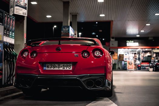 Red Nissan GT-R parked at a Sarajevo gas station at night, capturing urban automotive elegance.