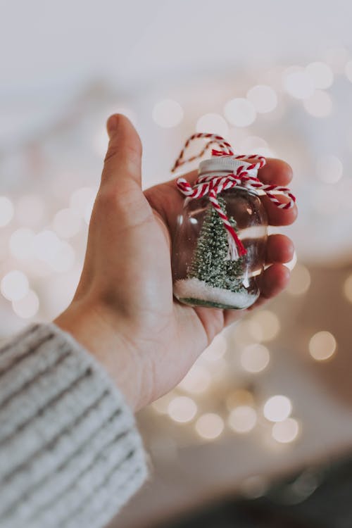 Shallow Focus Photo of Person's Hand Holding Glass Jar