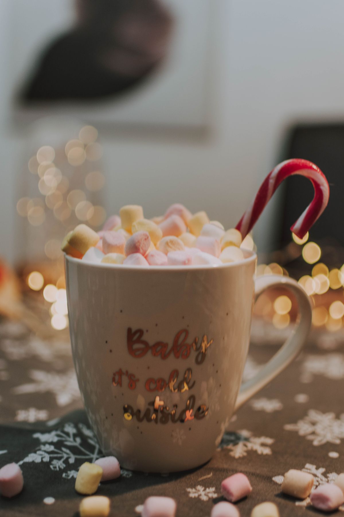 Warm marshmallow drink with a candy cane in a ceramic mug