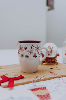 木桌上装饰着节日元素，特写镜头对准了一个圣诞节主题的杯子