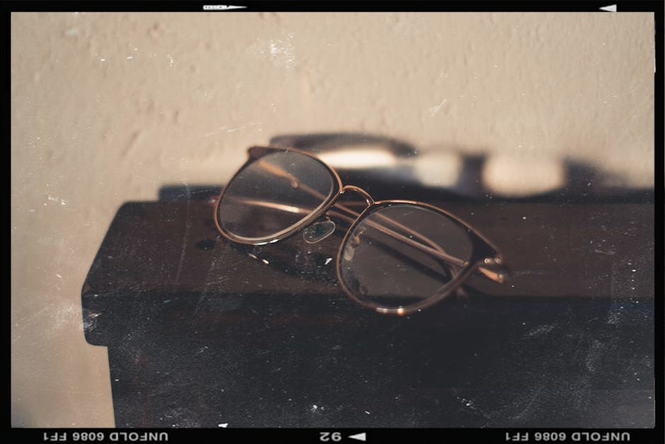 A close-up of vintage eyeglasses resting on a wooden surface with a classic aesthetic.