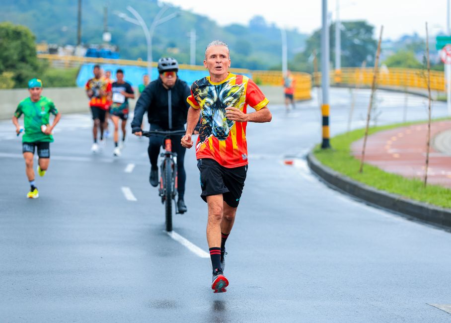 Elderly man running a marathon in a colorful shirt on a city road.