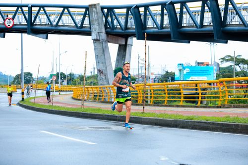 Free Man running in an urban marathon, showcasing athletic endurance and cityscape. Stock Photo
