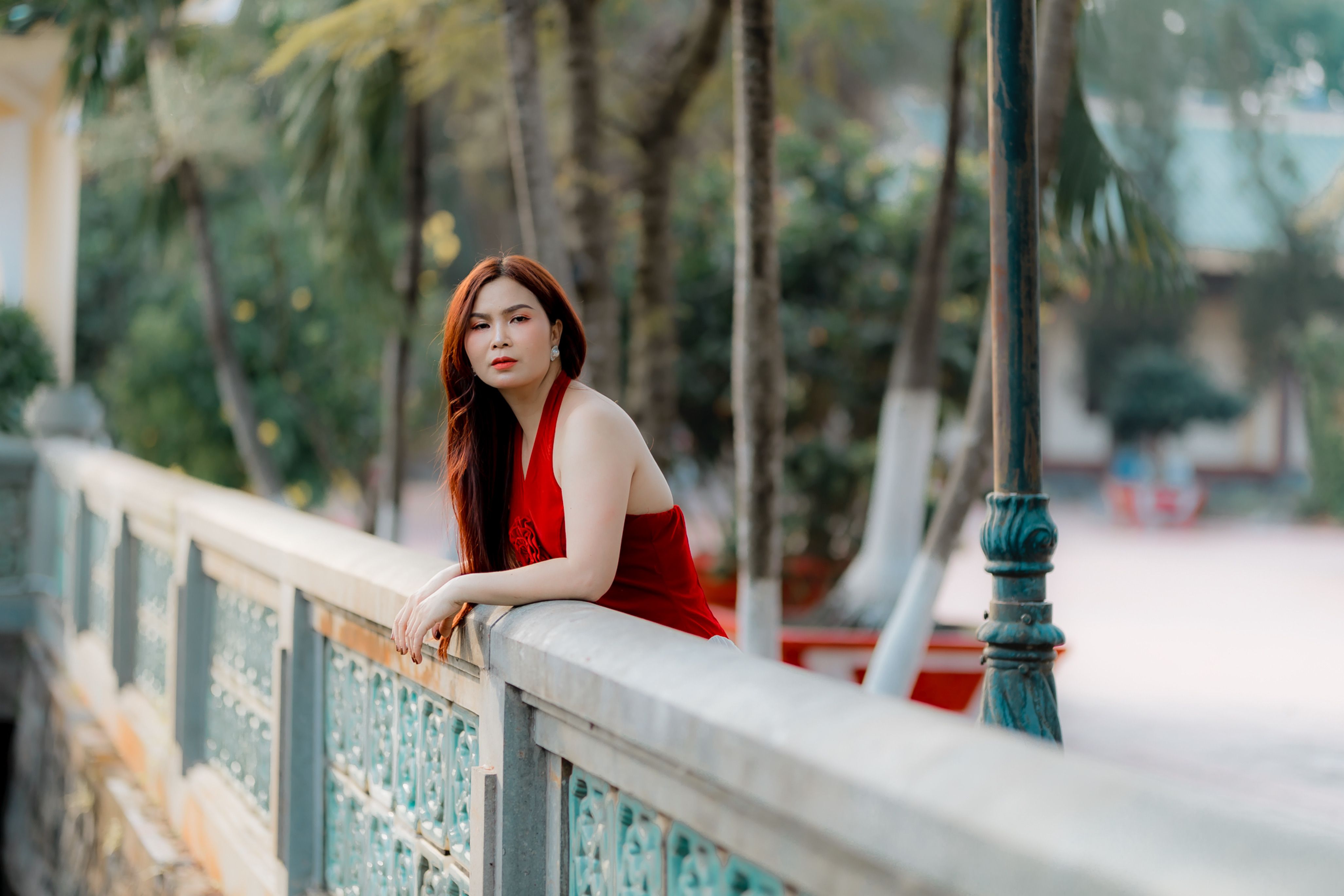 Young Woman in Red Dress Leaning on Balcony Outdoors · Free Stock Photo