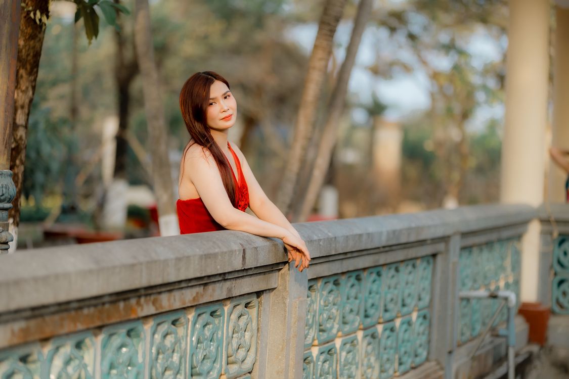 Resting On Railing Woman in Red Dress Resting on Decorative Railing · Free Stock Photo