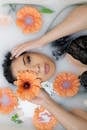 Woman Lying in Bathtub With Orange-Petaled Flowers