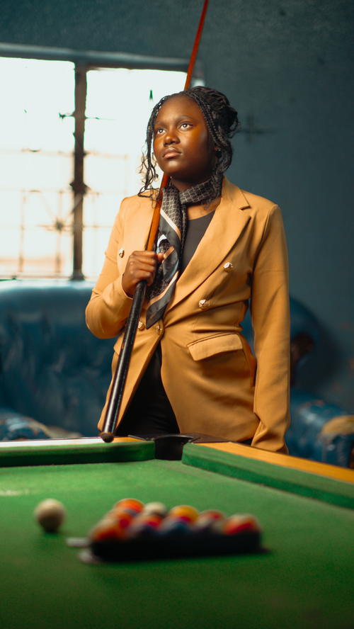 Free A confident young woman with a cue stick in a billiard hall, ready for play. Stock Photo
