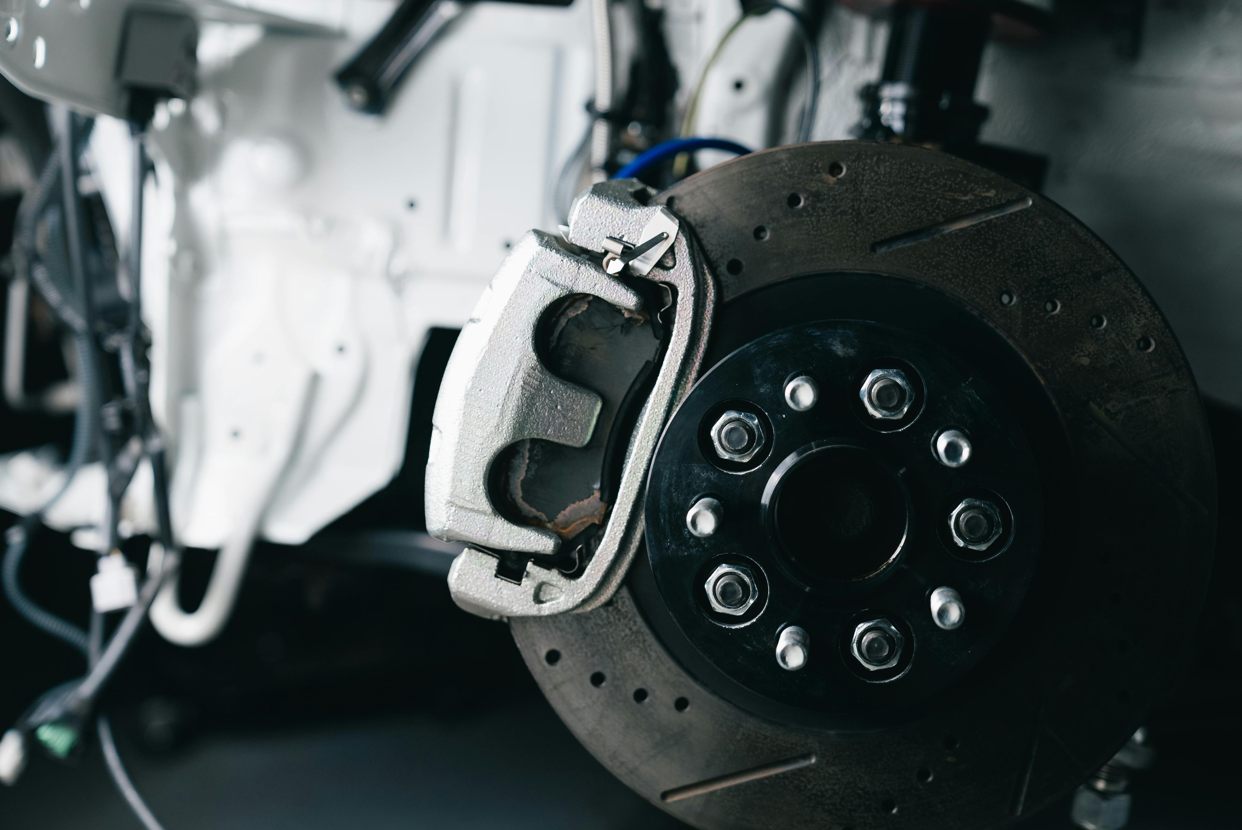 Detailed view of a car's brake caliper and disc in a workshop setting.