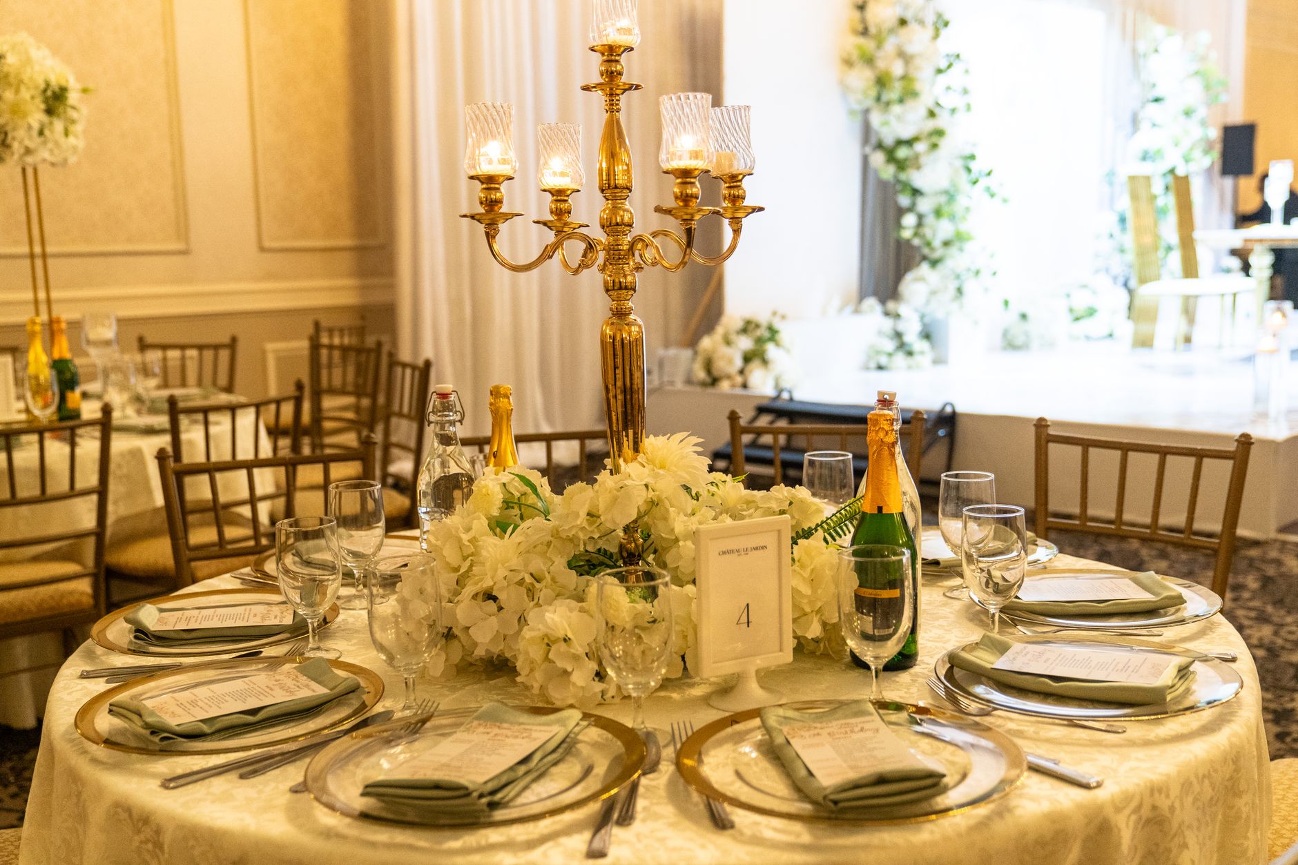 Luxurious wedding table decor featuring gold candelabra and white floral centerpiece, perfect for elegant events.