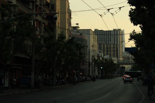Quiet city street at dusk with tall buildings in the background.