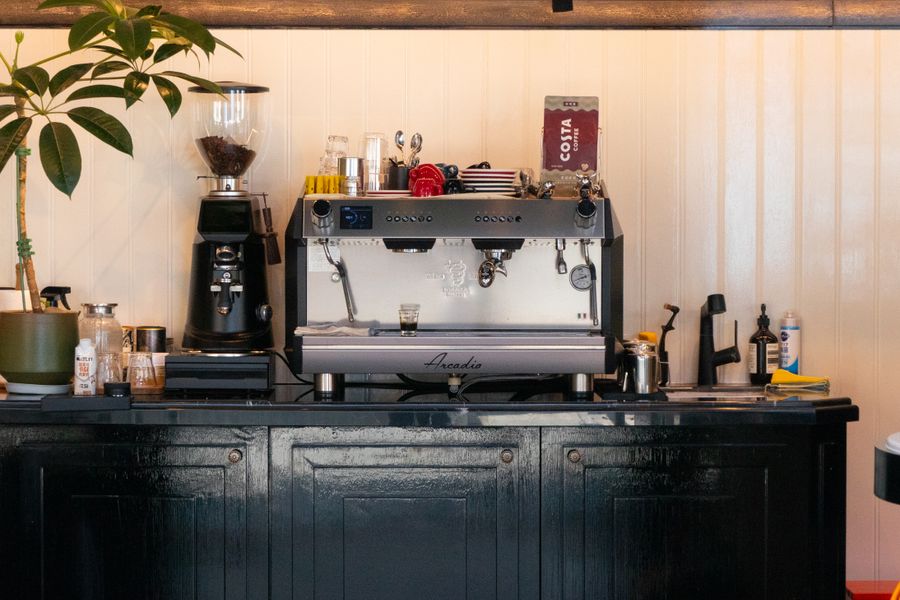 A charming coffee shop interior featuring a modern espresso machine and coffee grinder, evoking a warm, inviting atmosphere.