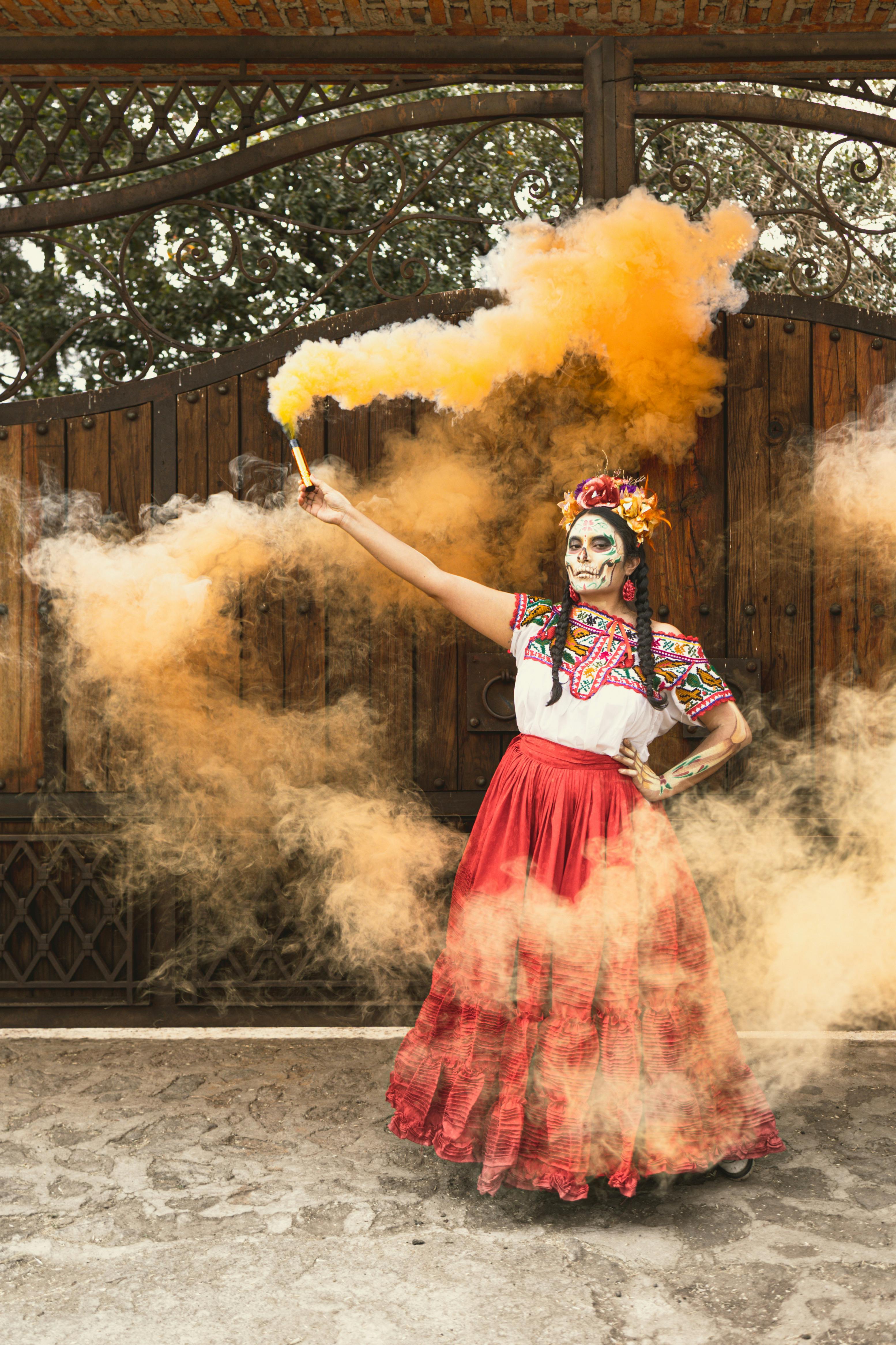 Vibrant Day of the Dead attire with smoke effects outdoors.