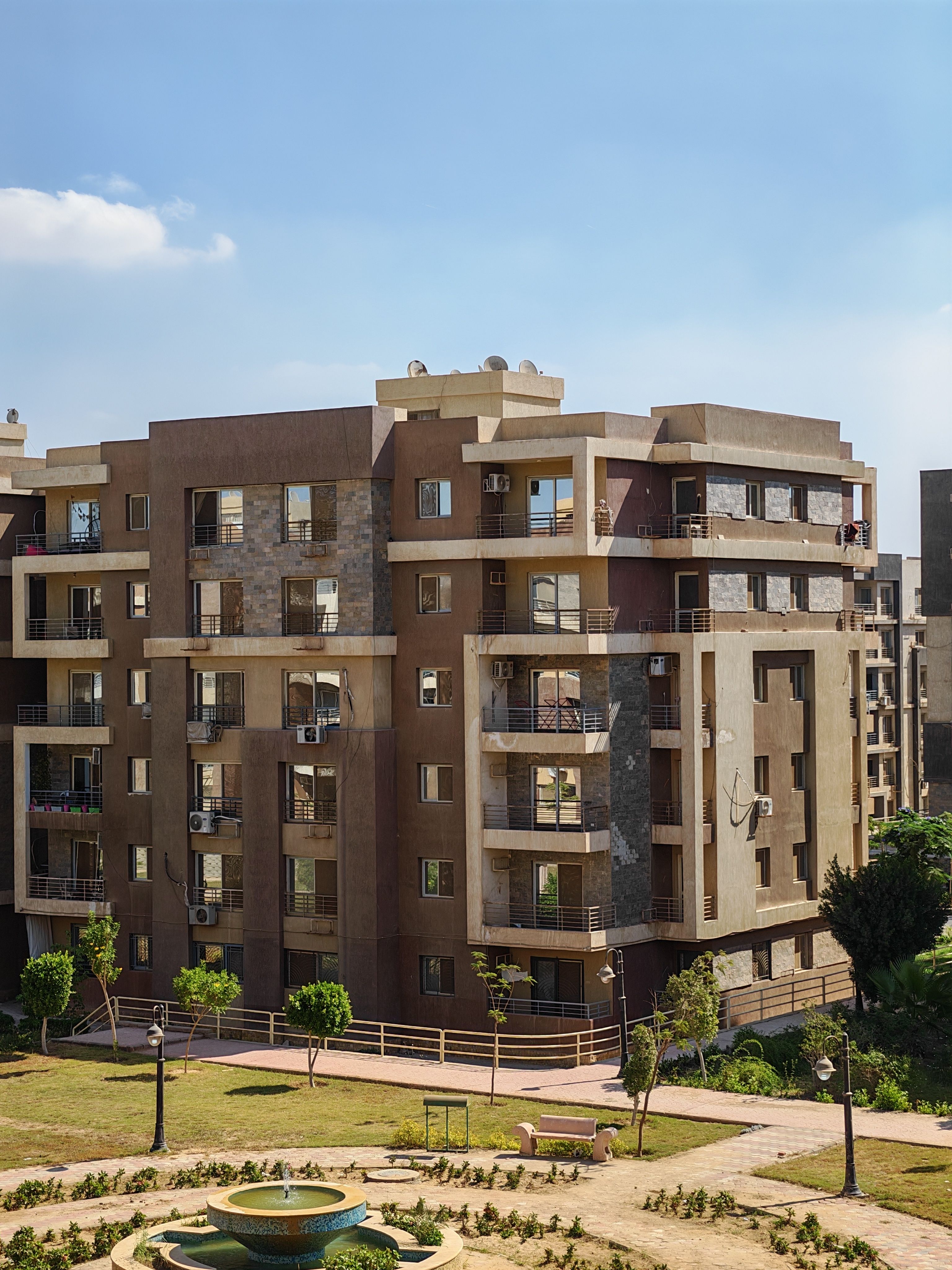 A contemporary apartment complex with a garden view under a clear sky.