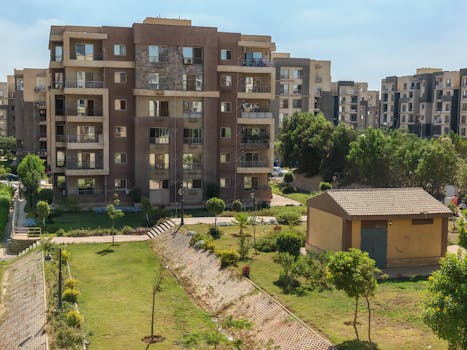 Photo by Mahmoud Zakariya A scenic view of a modern apartment complex surrounded by greenery under a clear blue sky.