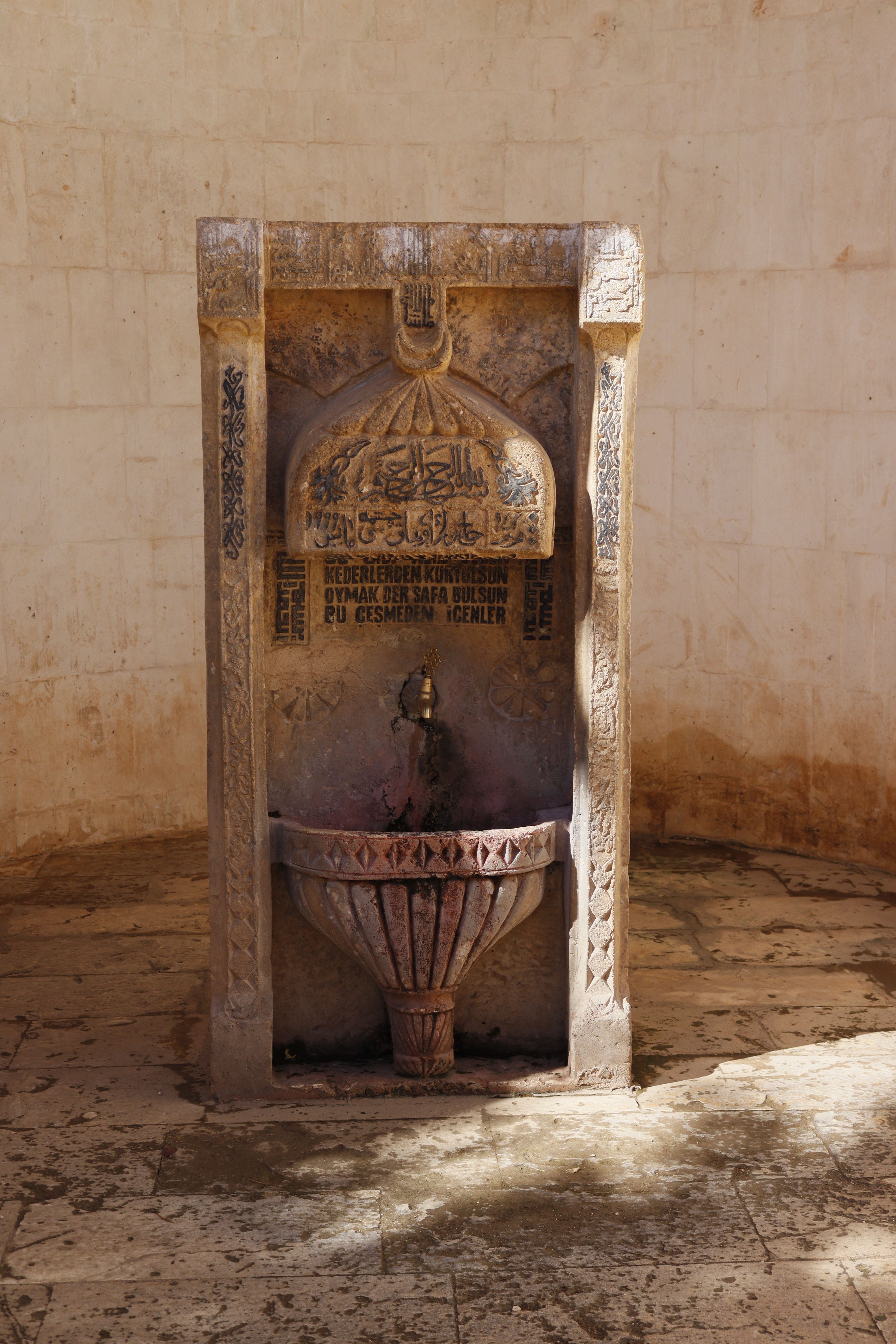 Historic stone fountain with Arabic script, captured in natural daylight.