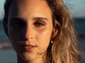 一个女人的特写肖像，她的脸上映着海滩上的阳光