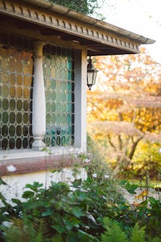 A Victorian house exterior with stained glass windows and fall foliage.