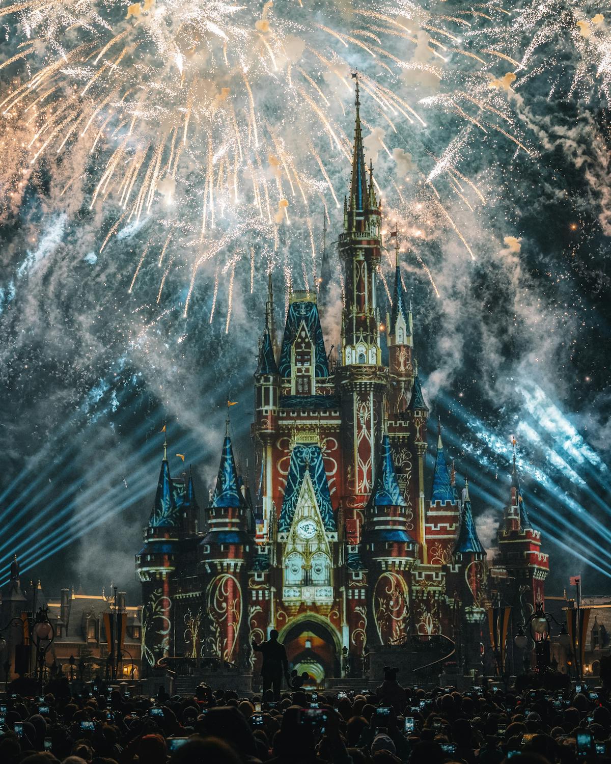Colorful Disney theme park castle at night with fireworks