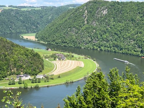 Free A breathtaking aerial view of a river bend surrounded by lush green hills and farmland. Stock Photo