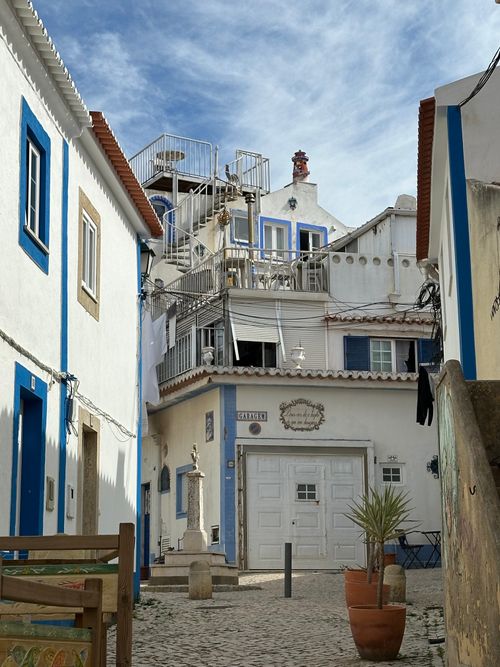 Free Quaint street scene in Ericeira, Portugal, featuring traditional architecture and vibrant blue accents. Stock Photo