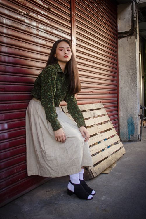 Free Asian woman in fashionable attire posing outside with wooden pallet backdrop. Stock Photo
