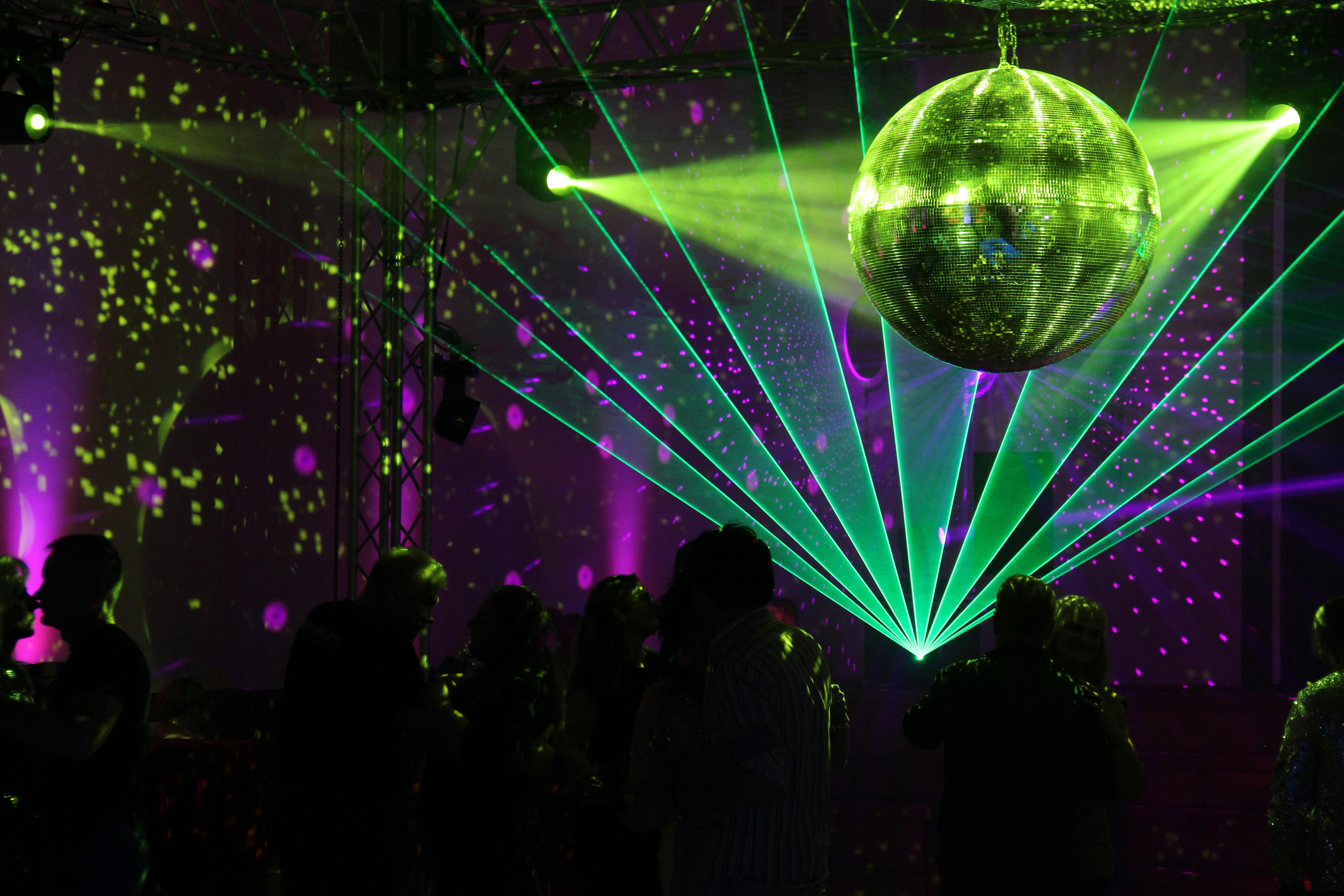 Colorful indoor disco scene featuring a sparkling disco ball and vivid laser lights.