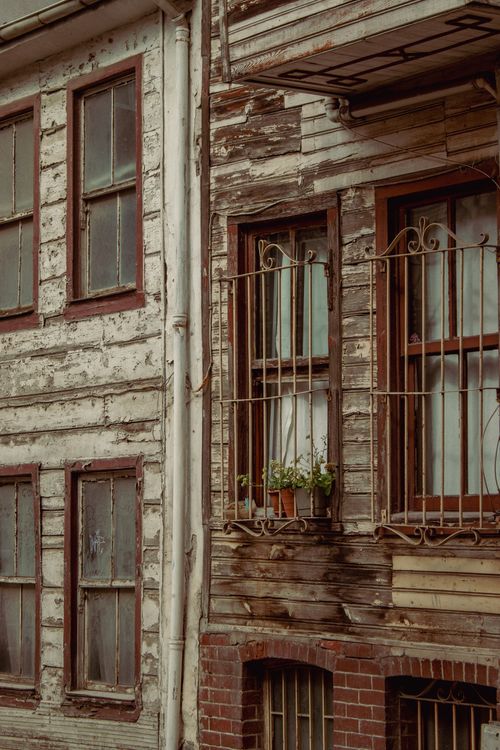 Free Close-up of a weathered rustic building facade with wooden textures and window bars. Stock Photo