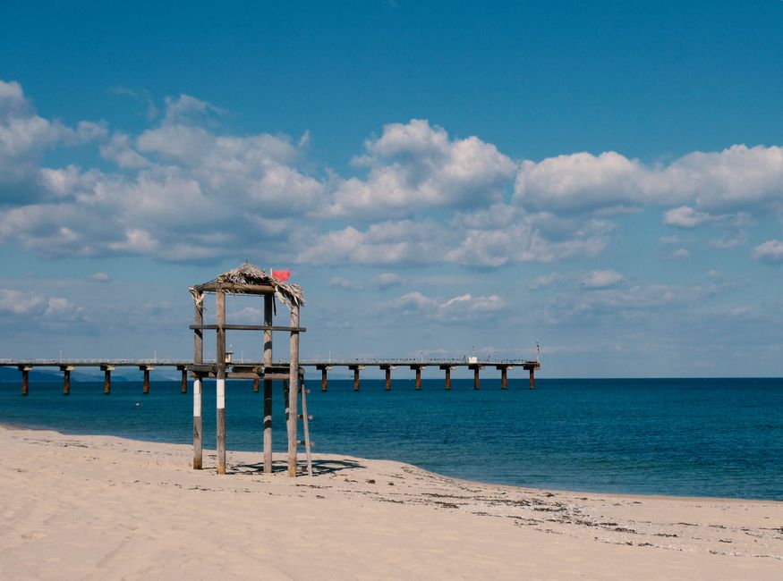 Peaceful beach scene with a wooden pier and lifeguard stand, perfect for relaxation.