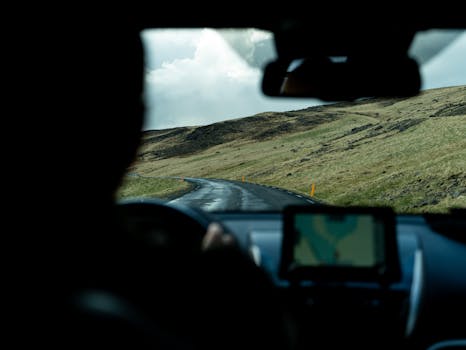 View from car driving through scenic Iceland landscape with hills and cloudy sky.