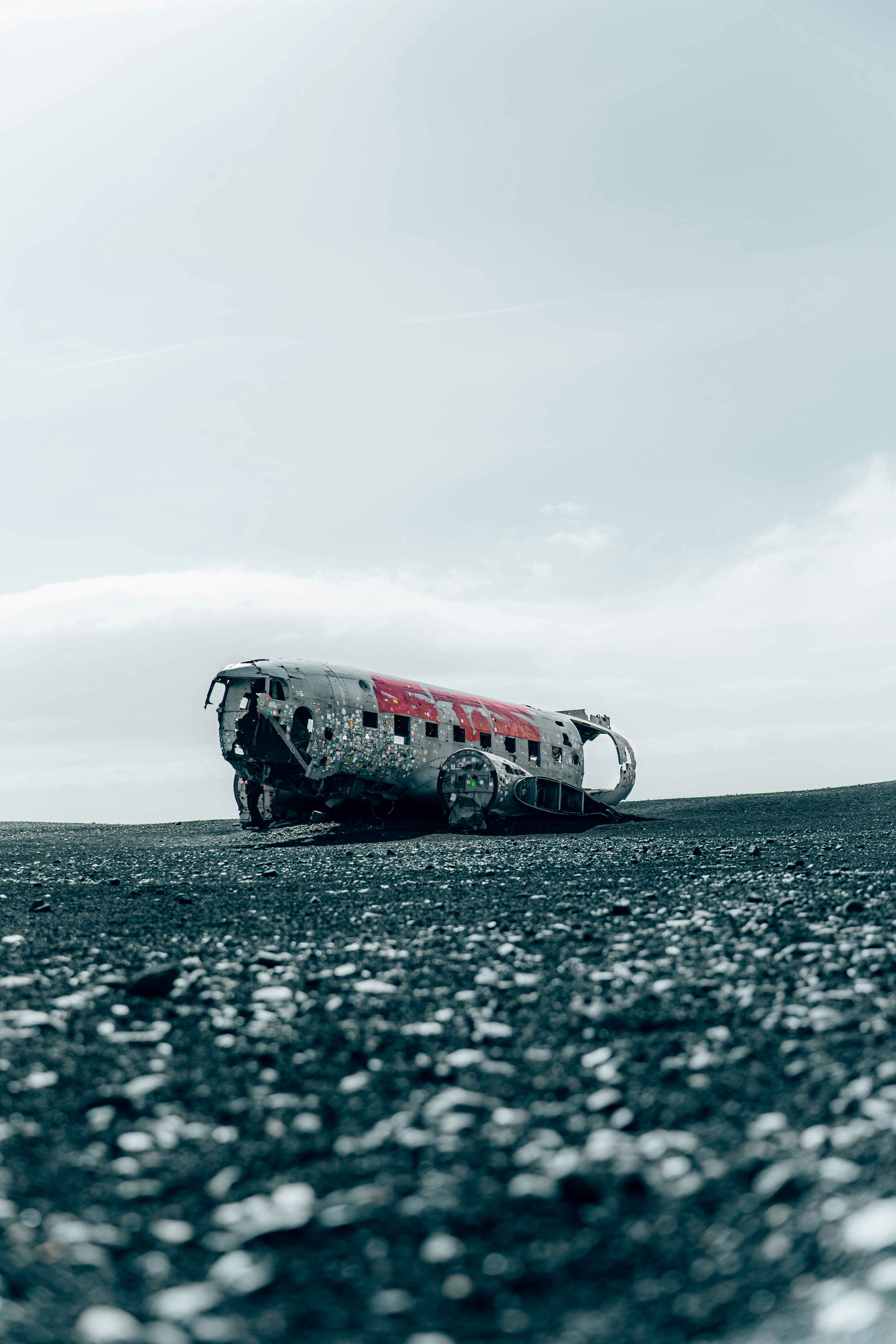 A lone abandoned plane wreck on a black sand beach in Iceland under a moody sky.