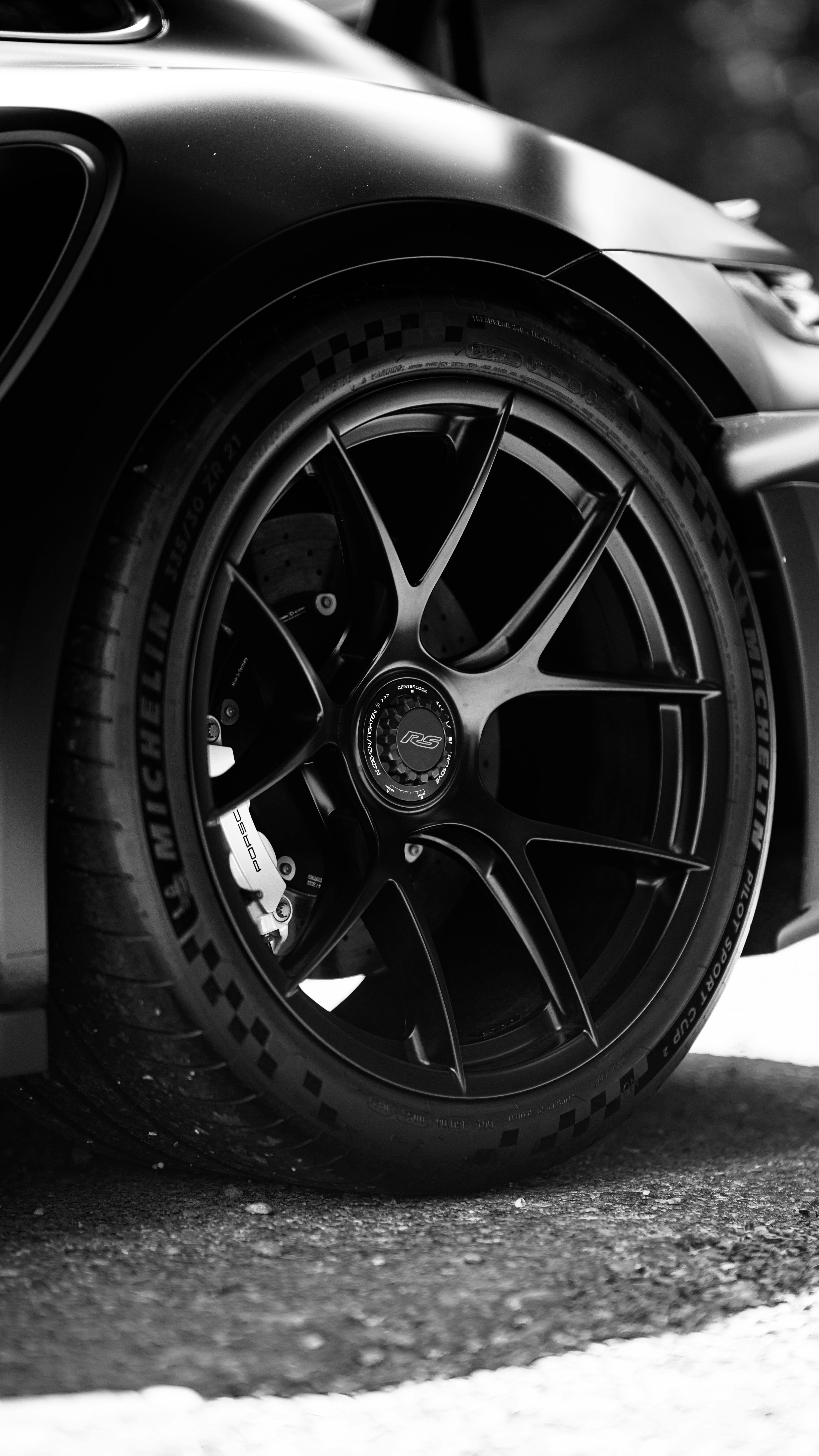 Free Black and white close-up of a sleek sports car wheel, showcasing its detailed design. Stock Photo