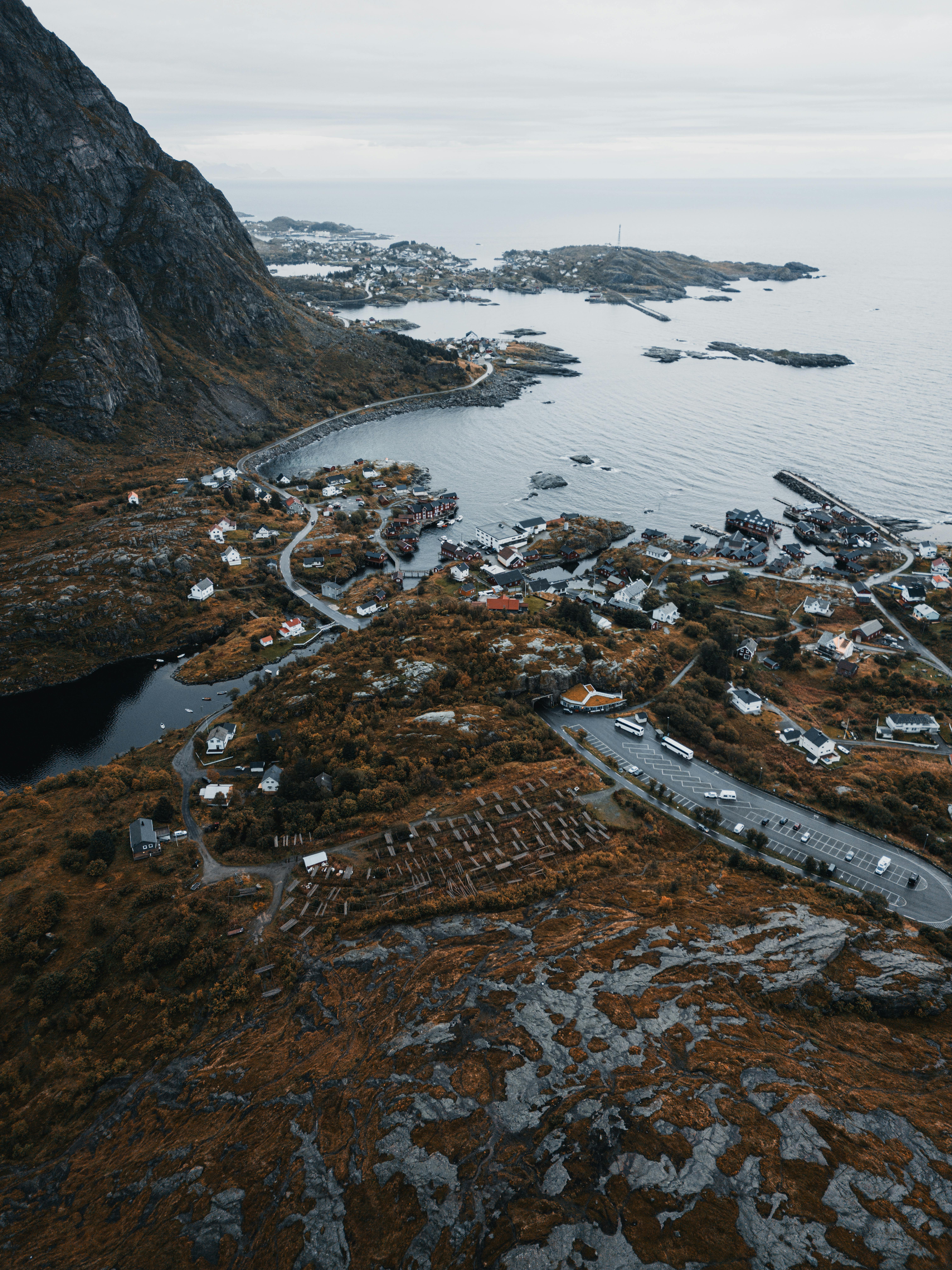 Aerial shot of a coastal town surrounded by mountains and sea in autumn.