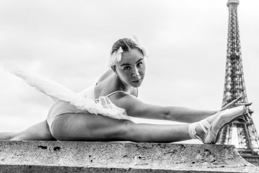 Graceful ballet dancer stretches with Eiffel Tower in the background.